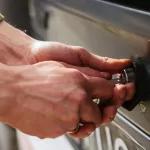 hands of a man unlocking car trunk with a key